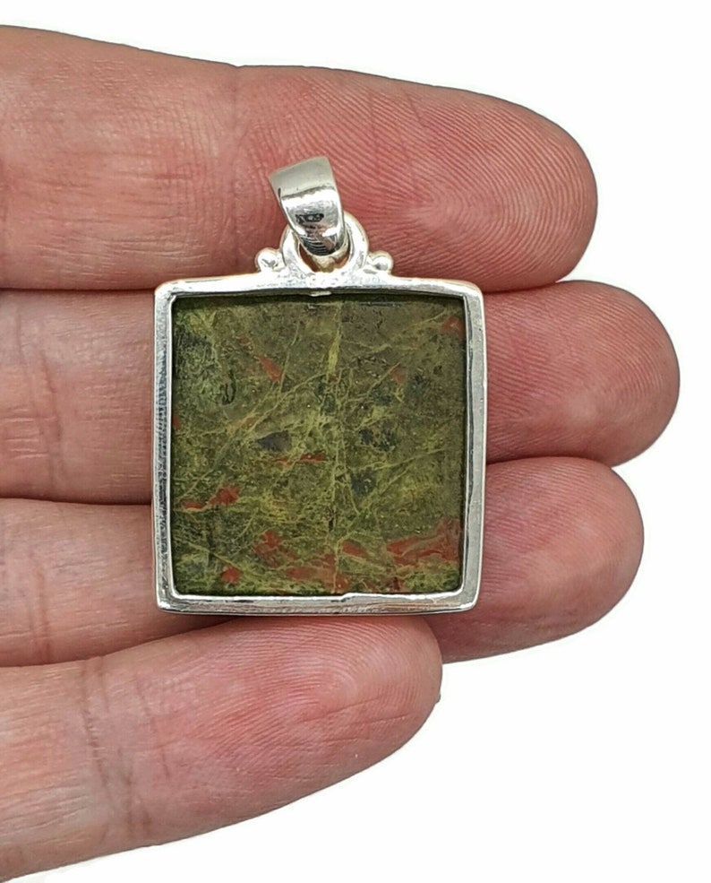 May include: A silver pendant with a square green and red jasper stone.