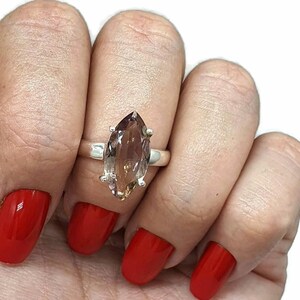 May include: A silver ring with a large, marquise-shaped, brown and purple gemstone.