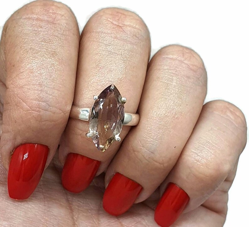 May include: A silver ring with a large, marquise-shaped, brown and purple gemstone.