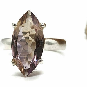 May include: A silver ring with a marquise-shaped amethyst gemstone. The gemstone is a light purple color with a slight brown hue.