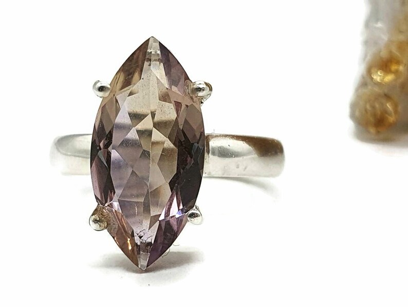 May include: A silver ring with a marquise-shaped amethyst gemstone. The gemstone is a light purple color with a slight brown hue.