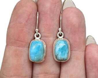 Pode incluir: Um par de brincos de prata pendurados com pedras retangulares de labradorita azul claro.