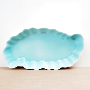 May include: A light blue ceramic serving dish with a scalloped edge.