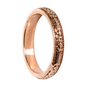 May include: A rose gold band ring with a floral design.