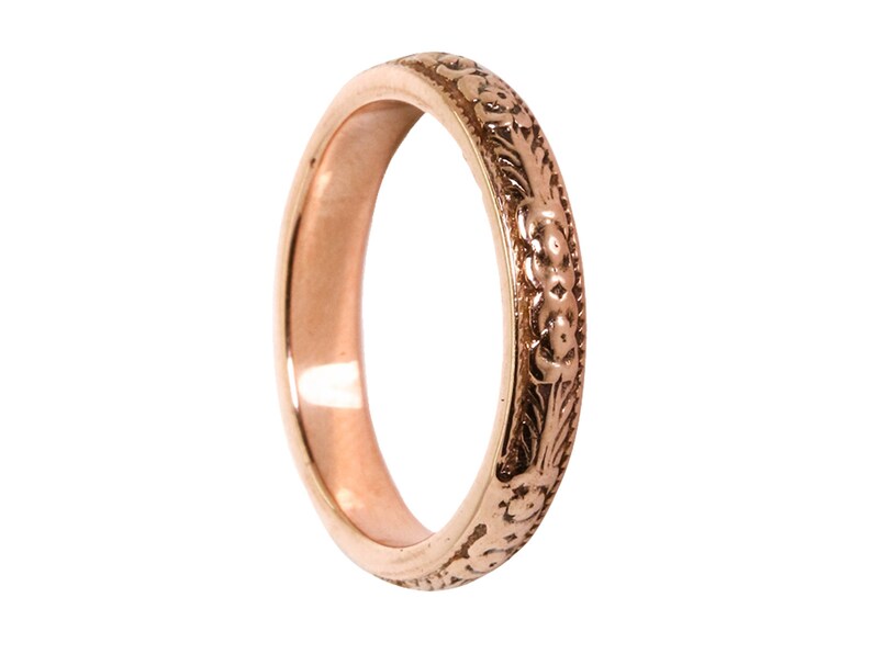 May include: A rose gold band ring with a floral design.