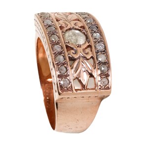 May include: A rose gold band ring with a delicate floral design and a single round diamond in the center. The band is set with smaller diamonds.