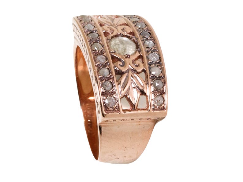 May include: A rose gold band ring with a delicate floral design and a single round diamond in the center. The band is set with smaller diamonds.