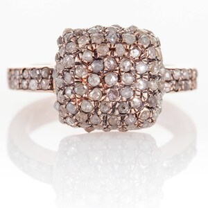 Peut inclure: Une bague en or rose avec une pierre centrale de forme carr&eacute;e sertie de petits diamants blancs. La bande est &eacute;galement sertie de petits diamants.