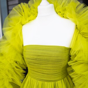 May include: A lime green tulle dress with a ruffled neckline and long sleeves. The dress is strapless and has a fitted bodice.