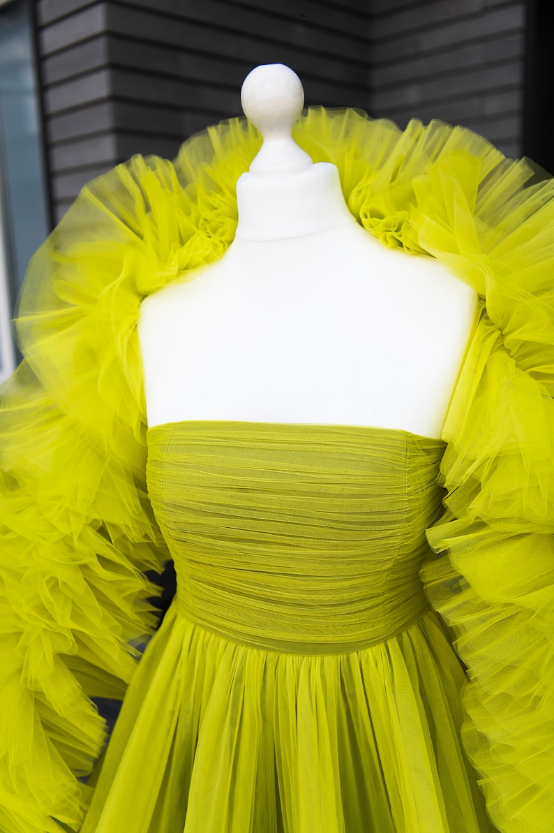 May include: A lime green tulle dress with a ruffled neckline and long sleeves. The dress is strapless and has a fitted bodice.