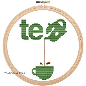 Pode incluir: Aro de bordado de ponto cruz com um bule de ch&aacute; verde despejando ch&aacute; em uma x&iacute;cara de ch&aacute; verde. A palavra "ch&aacute;" &eacute; bordada em verde.