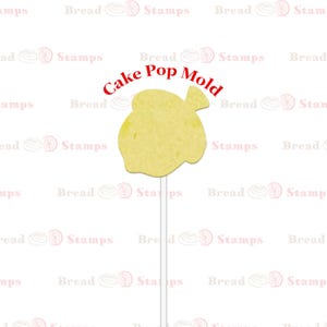 May include: A yellow cake pop mold in the shape of a fish. The mold is on a white stick and the text "Cake Pop Mold" is written in red above the mold.
