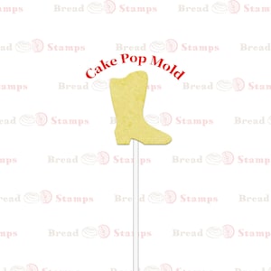 May include: A yellow cake pop mold shaped like a cowboy boot. The mold is on a white stick and has the words "Cake Pop Mold" written above it.