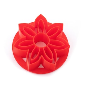 May include: Red plastic cookie cutter shaped like a flower with eight petals.