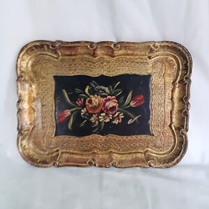 May include: Rectangular antique tray with a gold-coloured ornate frame. The centre features a dark background with a floral bouquet in shades of red, pink, yellow, and white. The tray has a scalloped edge.