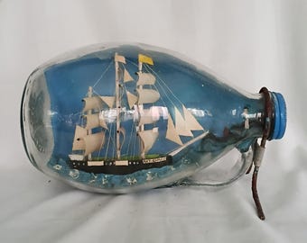 Barco vintage hecho a mano en una botella, arte popular, botella redonda bulbosa azul