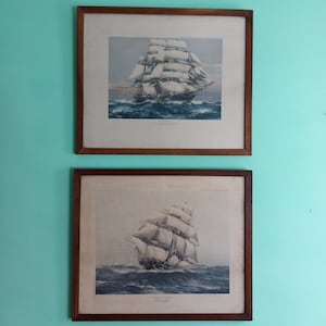 May include: Two framed prints of vintage sailing ships. The top print shows a ship called "The Flying Cloud" with the text "The Flying Cloud, the fastest ship in the world" below the image. The bottom print shows a ship called "Wyoming" with the text "Wyoming, the fastest ship in the world" below the image.