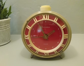 May include: A vintage green alarm clock with a red face and Roman numeral markings. The clock has a white knob on top and the word "Trempor" is printed on the face.