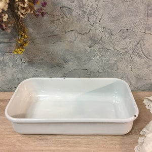 Puede incluir: Plato para hornear rectangular de esmalte blanco. El plato está vacío y tiene un ligero brillo.