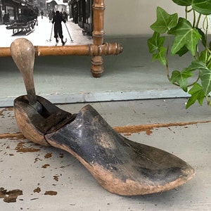 May include: A vintage wooden shoe stretcher with a dark brown finish and a metal lever. The stretcher is designed to help maintain the shape of shoes.