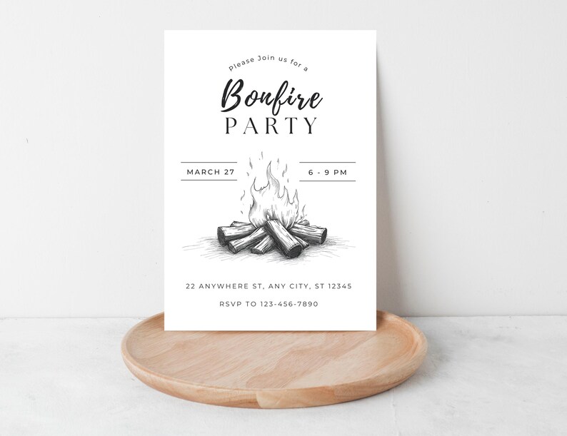 May include: A white invitation card with the words "Bonfire PARTY" in a stylish font, along with the date and time. A detailed illustration of a bonfire is featured. The card is placed on a wooden tray.