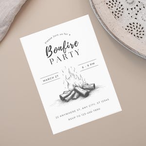 May include: A white invitation card with the text "Bonfire Party" in a script font. The card features a black and white illustration of a bonfire and the date March 27. The card also includes the time, address, and RSVP information.