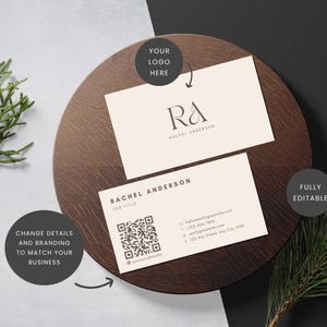 Puede incluir: Dos tarjetas de visita con el nombre "Rachel Anderson" y un logotipo, presentadas sobre una superficie de madera oscura. Las tarjetas tienen un diseño minimalista con información de contacto y un código QR. El texto "Totalmente editable" también es visible.