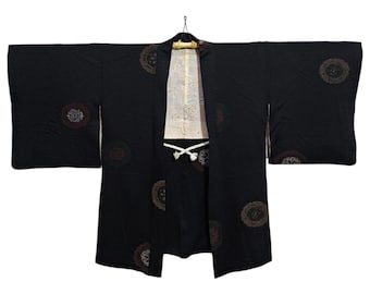 May include: A black Japanese kimono with a traditional pattern of brown and white circles. The kimono is hanging on a wooden hanger.