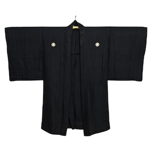Könnte beinhalten: Ein schwarzer japanischer Kimono mit goldenen Knöpfen. Der Kimono hängt an einem Kleiderbügel.