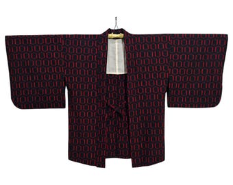 May include: A black and red patterned Japanese kimono with a geometric design. The kimono is hanging on a wooden hanger.