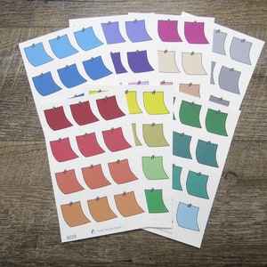 May include: A set of 10 sheets of colorful sticky note stickers. Each sheet has 6 stickers in a variety of colors, including blue, red, yellow, green, and orange. The stickers are designed to look like traditional sticky notes with a small black pin on the top.