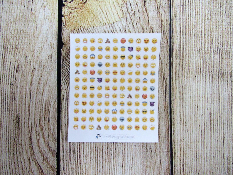 May include: A sheet of white paper with a grid of 100 yellow emoji stickers. The emojis include smiling faces, winking faces, hearts, sunglasses, and more. The sheet is labeled "Craft Penguin Press".
