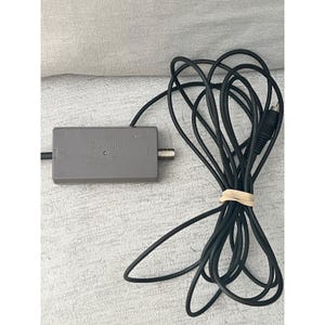 以下が含まれることがあります： グレーの任天堂RFスイッチモジュレーターボックスと黒いケーブル。長方形のデバイスには、任天堂のロゴ、モデル番号HVC-003、およびMade in Japanの文字が記載されています。長い黒いコードが巻かれ、輪ゴムで固定されています。