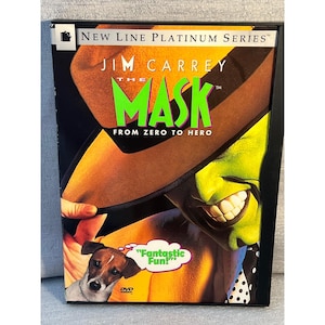 May include: A DVD case for the film The Mask, featuring Jim Carrey with a green face, wearing a brown hat. The cover includes the text New Line Platinum Series, The Mask, From Zero to Hero, and a speech bubble with the text Fantastic Fun! A small dog is visible in the lower left corner.