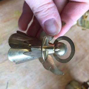 May include: A gold metal angel ornament with a halo and wings. The angel is holding a small ball in its hands.