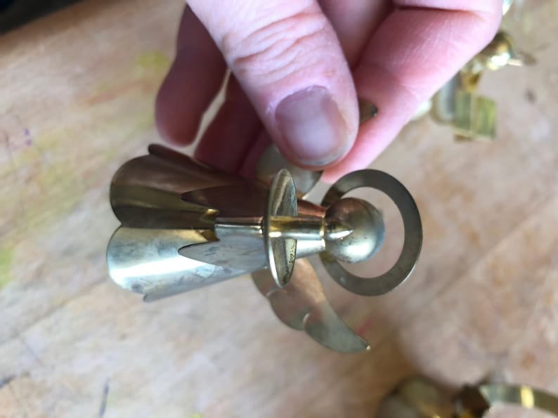 May include: A gold metal angel ornament with a halo and wings. The angel is holding a small ball in its hands.