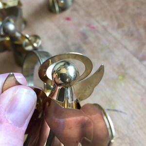 May include: Gold metal angel napkin ring with a halo and wings. The angel is holding a napkin.