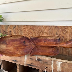 May include: A wooden serving dish with two sections, carved in the shape of a leaf. The dish is made of dark brown wood and has a natural finish.