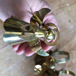 May include: A set of gold metal angel napkin rings. The angels have a bell-shaped skirt, wings, and a halo.