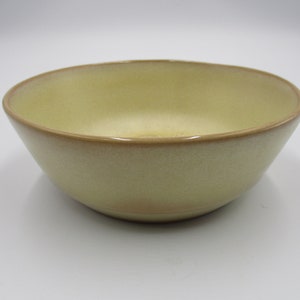 May include: A light yellow ceramic bowl with a brown rim. The bowl has a speckled texture.