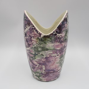 May include: A ceramic vase with a unique marbled design in shades of purple, green, and white. The vase has a wide opening and a narrow base.