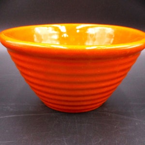May include: A bright orange ceramic bowl with a ribbed design. The bowl is empty and has a glossy finish.