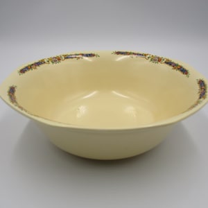 May include: A large, cream-colored serving bowl with a floral pattern around the rim. The bowl is made of ceramic and has a slightly rounded shape.