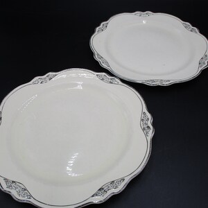 May include: Two white ceramic plates with a scalloped edge and a silver floral design around the rim.