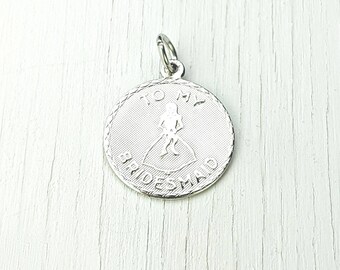 May include: Silver charm with a scalloped edge and the words "To My Bridesmaid" and a small image of a woman in a wedding dress.