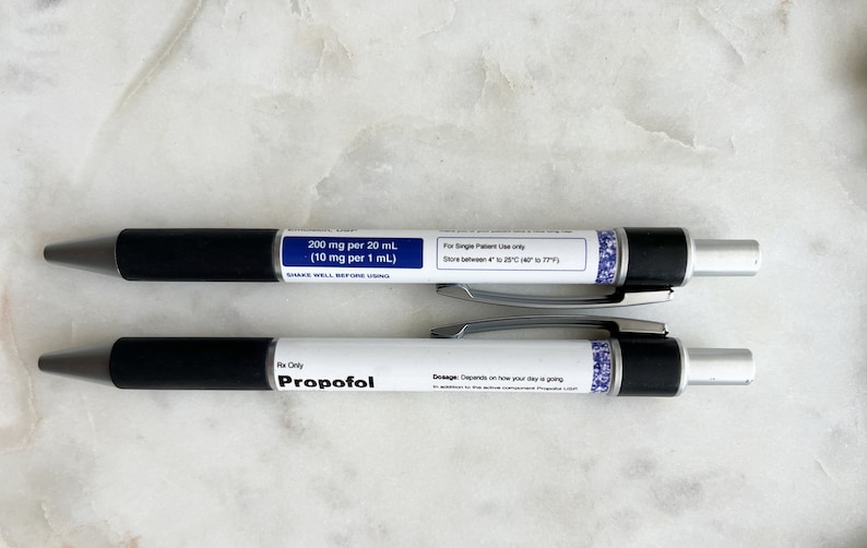 Pode incluir: Duas canetas pretas e prateadas com etiquetas brancas. A caneta superior tem o texto "200 mg por 20 mL (10 mg por 1 mL)" e "Para uso exclusivo de um &uacute;nico paciente. Armazenar entre 4&deg; e 25&deg;C (39&deg;F e 77&deg;F)". A caneta inferior tem o texto "Rx Only Propofol" e "Dosagem: Depende de como est&aacute; sendo o seu dia".