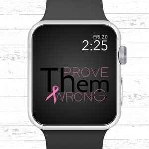 May include: A black and silver Apple Watch with a black band. The watch face displays the time "2:25" and the date "FRI 20". The text "PROVE THEM WRONG" is displayed on the watch face with a pink ribbon.