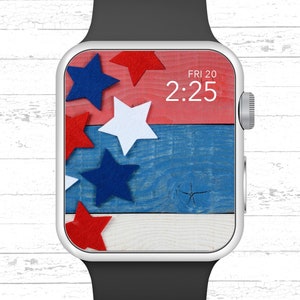 Peut inclure: Une Apple Watch argent&eacute;e avec un bracelet noir affiche un cadran de montre sur le th&egrave;me du drapeau am&eacute;ricain rouge, blanc et bleu avec l'heure 2:25 et la date VEN 20.