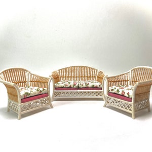 May include: A white wicker sofa set with floral cushions. The set includes a loveseat and two armchairs.