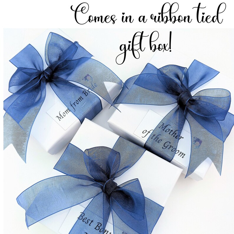 May include: White gift boxes tied with sheer navy blue ribbons. Each box has a label with text, including "Mom from Bride", "Mother of the Groom", and "Best Bon". The image also includes the text "Comes in a ribbon tied gift box!"
